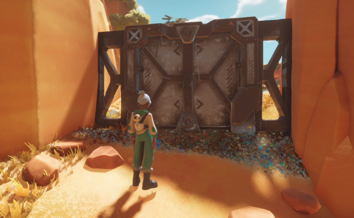 An explorer standing before a huge metal gate in a canyon